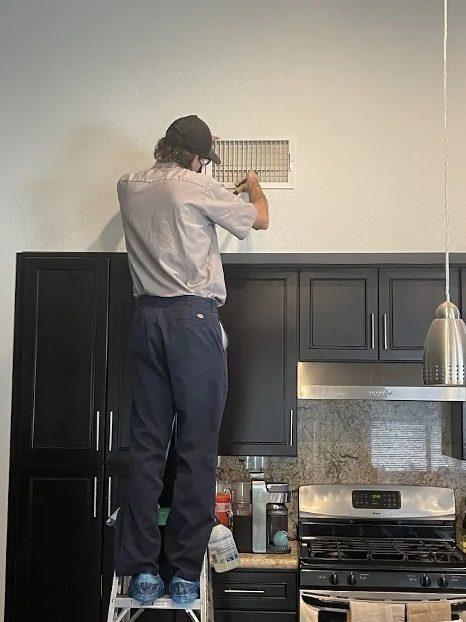 Technician inspecting an air vent during HVAC service in Hillsboro